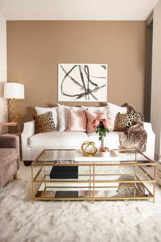 a living room with white couches and pillows on top of the rugs in front of a coffee table