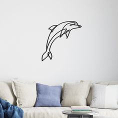 a living room with a white couch and a dolphin wall decal on the wall