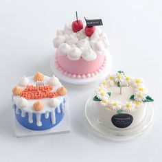 three small cakes are sitting on top of each other, one is white and the other is pink