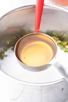 a pot filled with liquid sitting on top of a white counter next to a red spatula