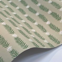 a wallpaper with green leaves and white flowers on beige paper, which is folded to the side