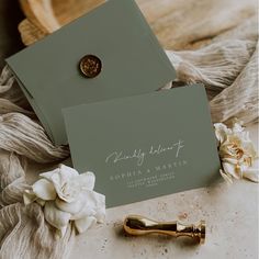 two green cards with white flowers and a gold tie clip sitting on top of each other