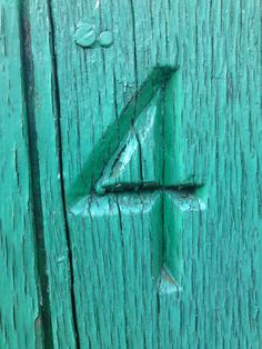 the number four is painted on a green wooden door with drops of water around it