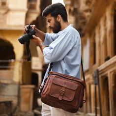 a man with a beard holding a camera bag