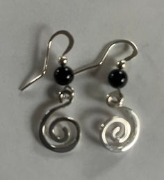 Handmade sterling silver spirals are formed, hammered, and polished to catch the light. I've made earwires with 6mm black onyx beads. All sterling silver, made by me in my Maine studio. The spirals are about 1/2-5/8" in diameter and the total length from the hole in your earlobe to the bottom of the earring is 1 1/2". Small rubber ear nuts provide security. These will be perfect with your little black dress, or for every day. E435. Gift boxed and free shipping. Elegant Black Spiral Jewelry, Black Spiral Earrings As Gift, Black Spiral Earrings For Gift, Black Sterling Silver Hand Forged Jewelry, Black Hand Forged Sterling Silver Jewelry, Hand Forged Black Sterling Silver Jewelry, Black Hand Forged Dangle Jewelry, Nickel-free Black Spiral Jewelry, Spiral Earrings