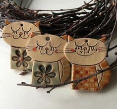 three ceramic cats sitting on top of a wooden branch next to a twig wreath