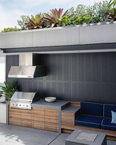 an outdoor kitchen with grill, seating and potted plants on the roof terrace area