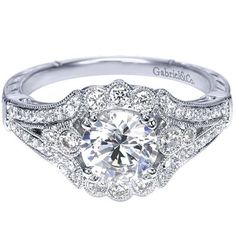 a white gold engagement ring with an intricate halo setting and round brilliant cut diamonds on the band