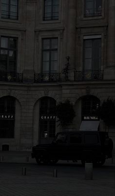 a black truck parked in front of a tall building with windows and balconies