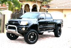 a black toyota truck parked in front of a house