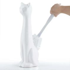 a person holding a toothbrush in front of a white cat figurine with wings