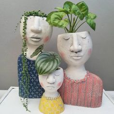 three ceramic heads with plants growing out of them