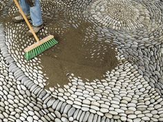 a person with a broom is cleaning some rocks on top of a large circular table