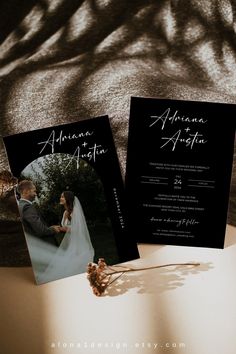 two black and white wedding cards sitting on top of a table