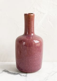 a red vase sitting on top of a white counter