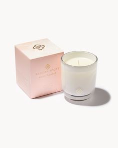 a white candle next to a pink box on a white surface with the lid open