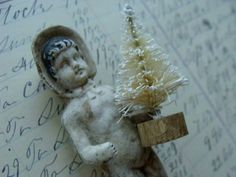 a small figurine holding a christmas tree on top of a piece of paper