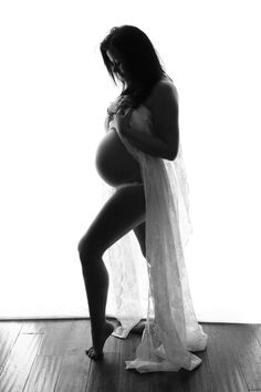 a pregnant woman is standing on the floor with her hands behind her back and legs crossed