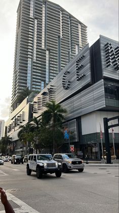 cars are driving down the street in front of tall buildings