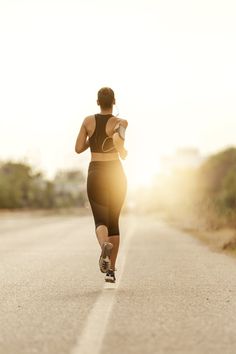 a woman running down the road at sunset