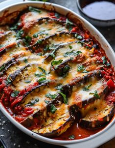 an oval casserole dish filled with eggplant, cheese and tomato sauce