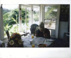 a woman sitting at a table writing on a piece of paper in front of a window