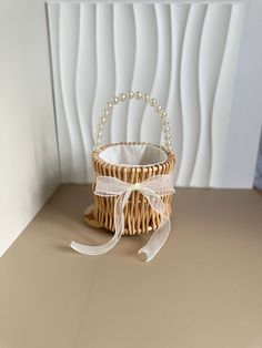 a wicker basket with a white ribbon tied around it on a table next to a wall