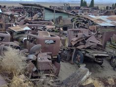 an old junkyard full of rusted out cars and trucks in the middle of nowhere