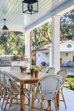 an outdoor kitchen and dining area with grill in the back yard, covered by a pergolated roof