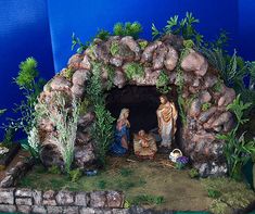 a nativity scene with figurines in the mangeroom, surrounded by greenery and rocks