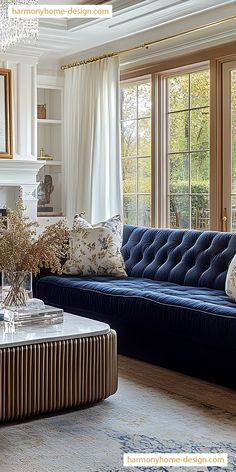 a living room with blue couches and white curtains in front of large windows that look out onto the woods