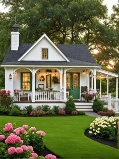 a white house with green shutters and flowers in the front yard on a sunny day