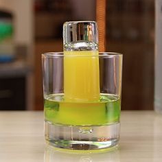 a glass filled with liquid sitting on top of a table next to a bottle of orange juice