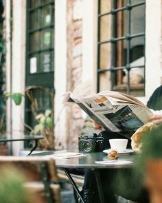 a person sitting at a table reading a newspaper