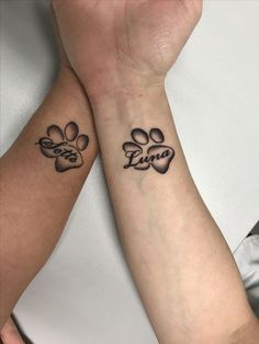 two people with matching tattoos on their arms holding hands, one has a paw and the other has a heart