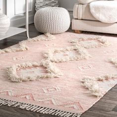 a pink rug with tassels on the floor in a white living room area