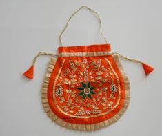 an orange bag with tassels and flowers on the front is hanging from a string