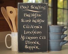 a chalkboard sign sitting on top of a counter next to cups and spoons