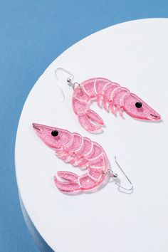 Let's take a trip under the sea. Get ready to set sail with our dazzling pink shrimp earrings! These whimsical and weird little gems are shrimply irresistible. Whether you're catching rays beachside or lighting up the dance floor, our shrimp companions are your perfect transition from sunshine to starlight. Shrimp charms measure 2 inches long and 1.5 inches wide. With the wire, they hang about 2.75 inches long.  Crafted from glittering pink acrylic, each shrimp is carefully laser engraved, cut, Fun Pink Jewelry With Lobster Clasp, Pink Novelty Earrings, Pink Novelty Jewelry With Lobster Clasp, Novelty Pink Jewelry With Lobster Clasp, Pink Novelty Earrings For Party, Shrimp Jewelry, Shrimp Earrings, Pink Shrimp, Louisiana Gifts