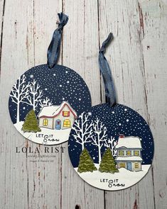 two handmade christmas ornament hanging on a wooden surface with snow and trees