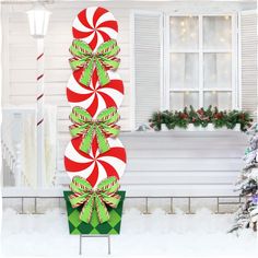 a large candy cane decoration in front of a house with christmas decorations on the porch