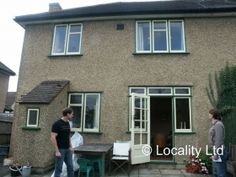 two men are standing in front of a house