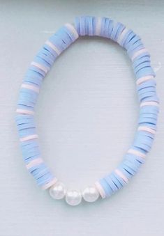 a blue and white beaded bracelet with two pearls on the end, sitting on a table