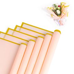 four pink and yellow paper with flowers on top next to it, one folded in half