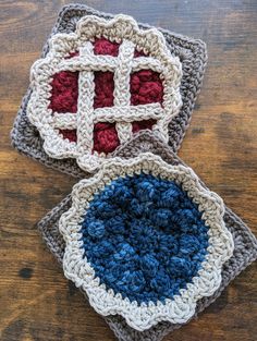 three crocheted coasters with red, white and blue designs on them sitting on a wooden surface