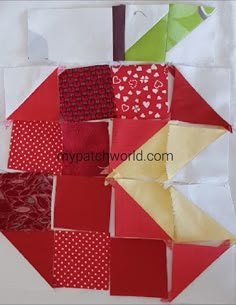 an apple made out of red and white fabric with hearts on the side, sitting on top of a piece of paper