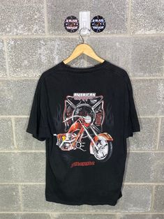 a t - shirt hanging on a brick wall next to a hanger with an image of a motorcycle