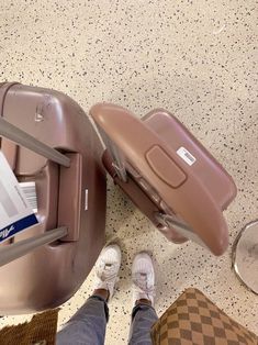 two pieces of luggage sitting on top of a floor next to someone's feet