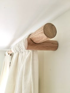 a curtain rod with a wooden handle hanging from it's side in front of a window