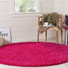 a bright pink rug in the corner of a room with a chair and coffee cup